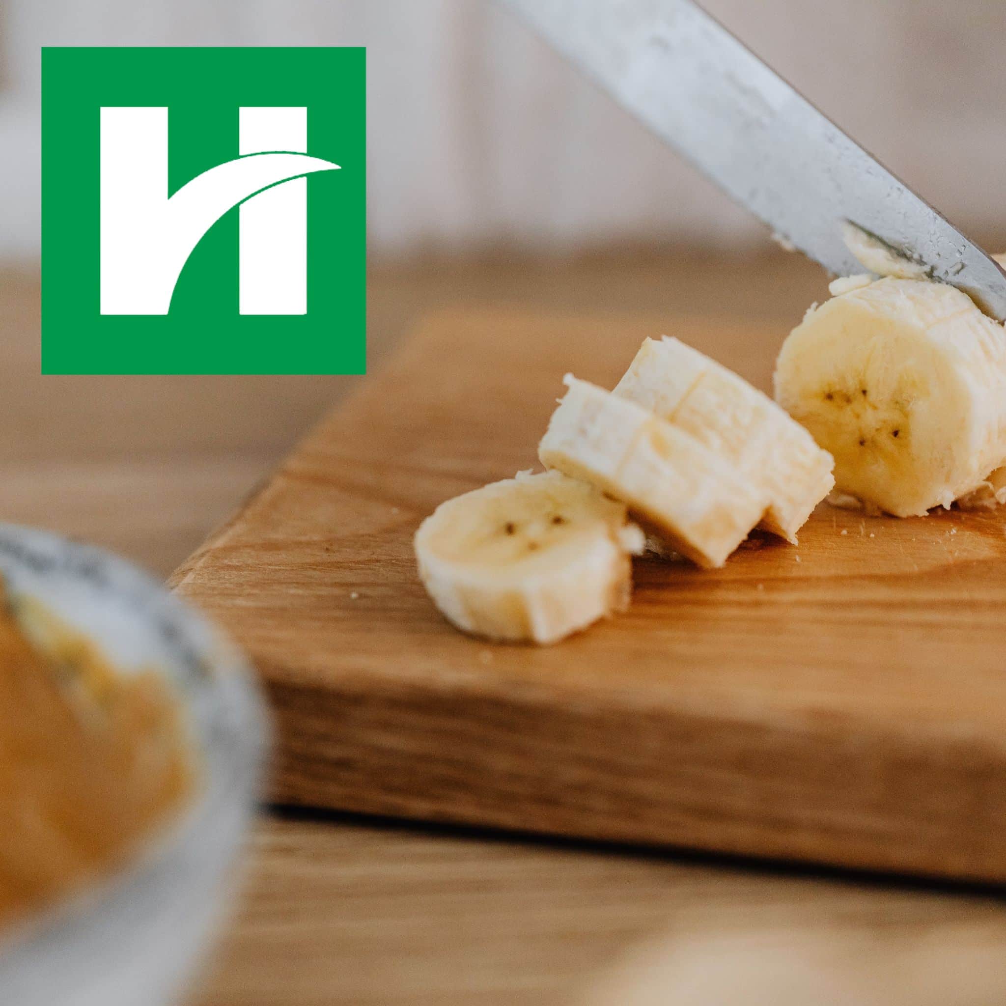 Banana slices on a table next to a jar of peanut butter