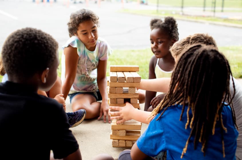 Several children playing with a stacking block game