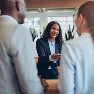 woman behind desk handing materials to hotel guest job career professional
