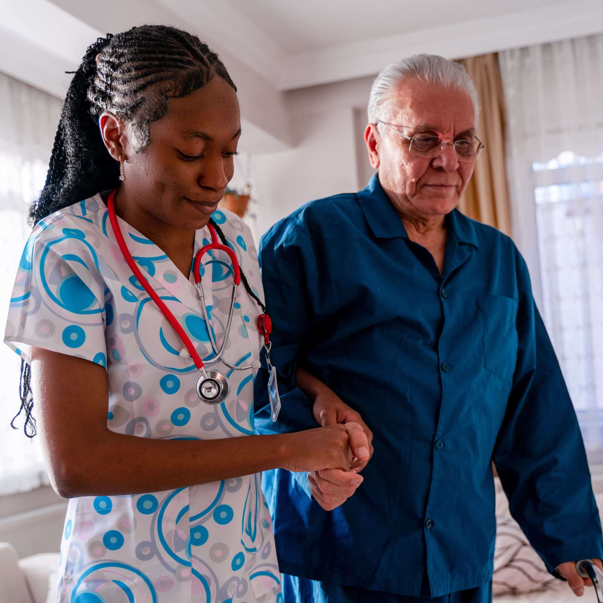 woman in healthcare attire supporting man walking