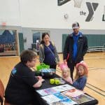A family standing near a booth at the Witham Family YMCA