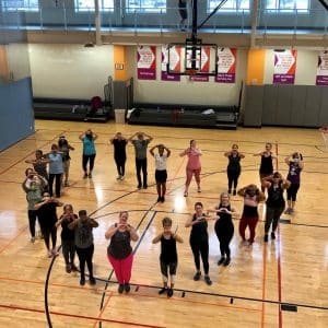 Zumba class in a gym with members standing in a heart shape