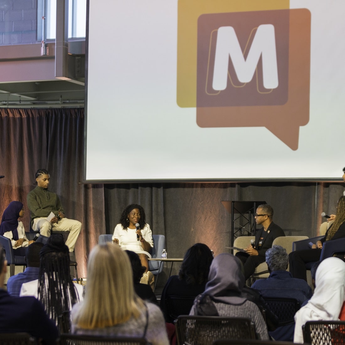 The audience listens and watches a panel of speakers at the Monster Meeting.