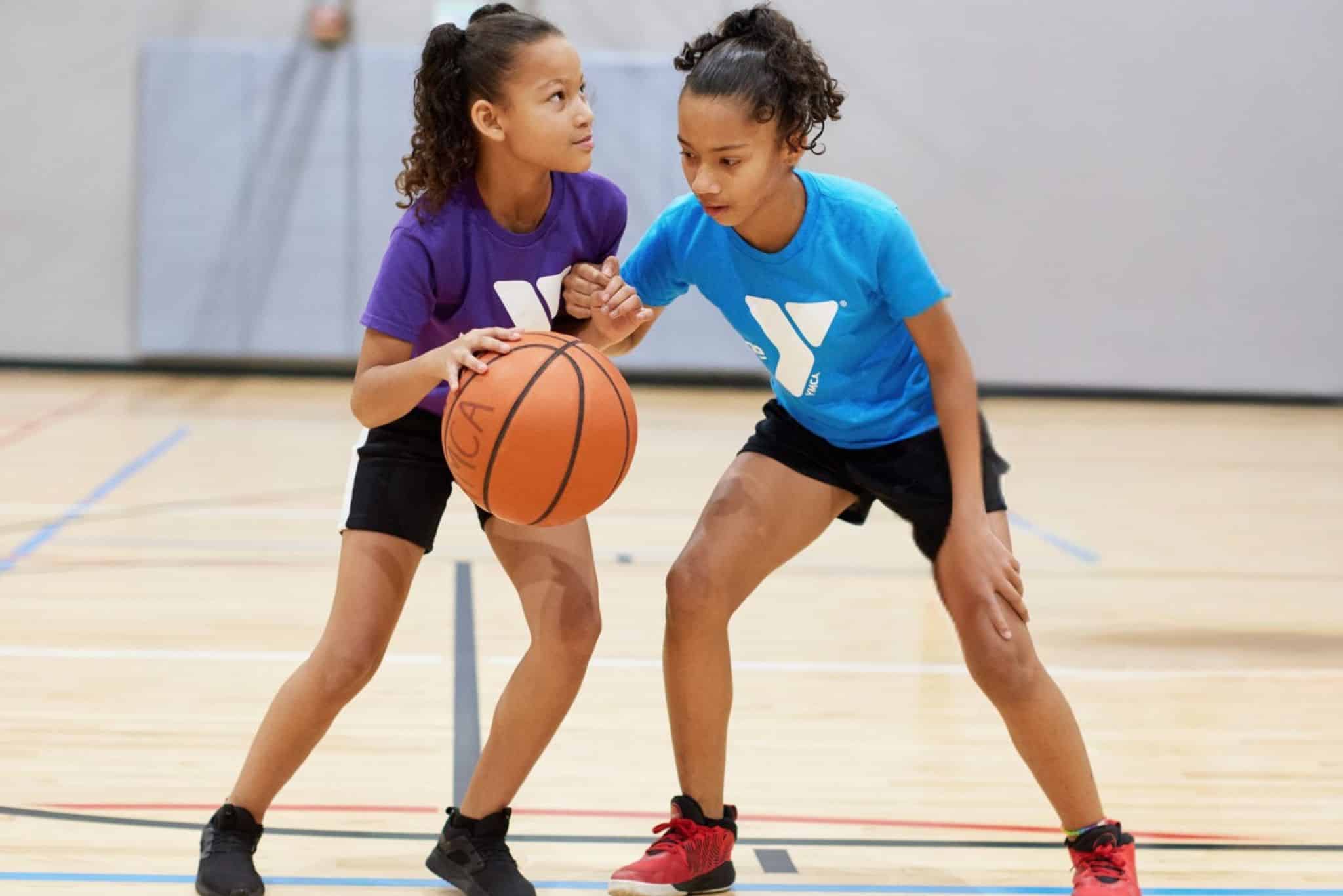 Two girls play basketball in a YMCA basketball league