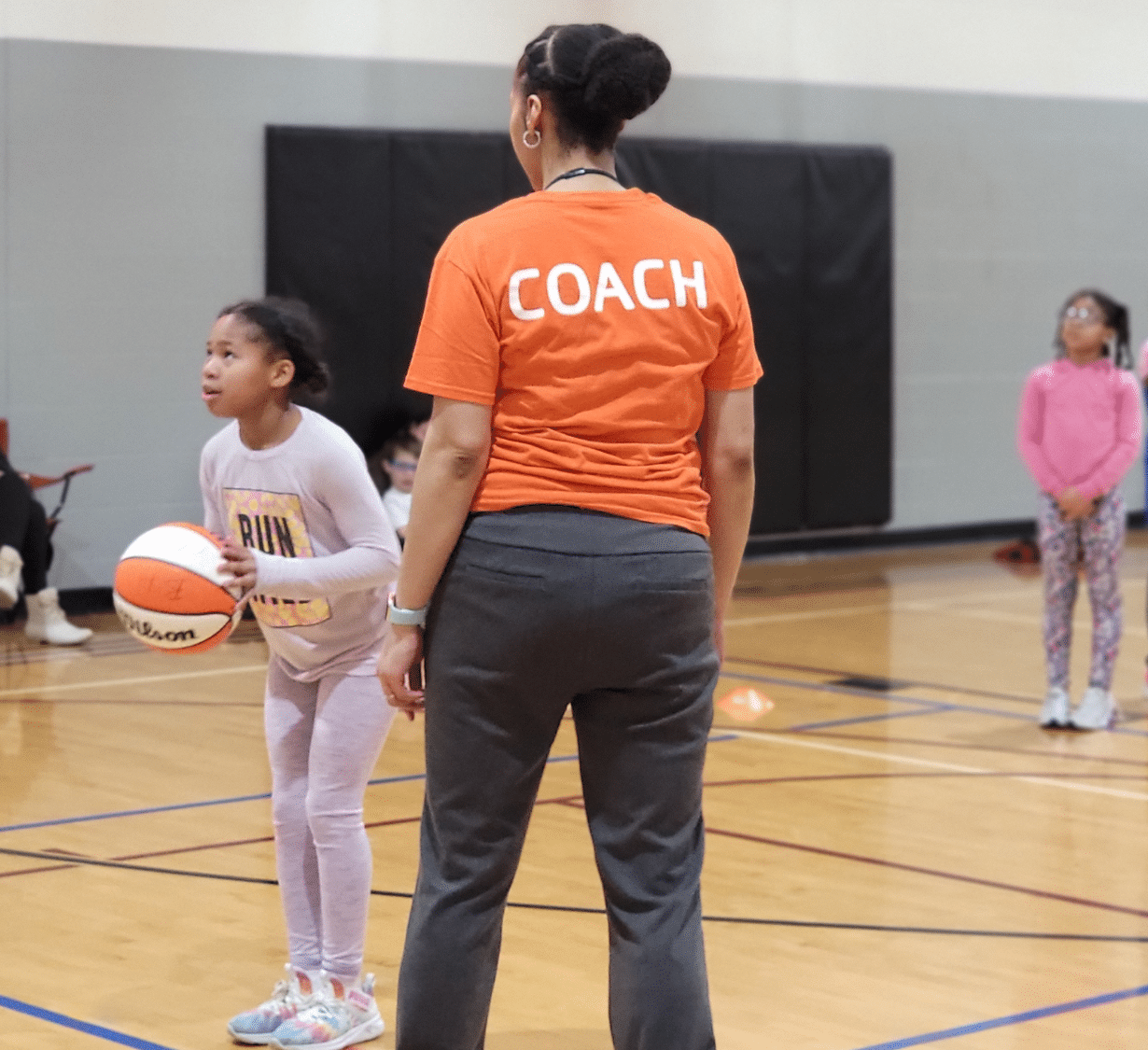 Girls practice shooting at a YMCA basketball clinic.