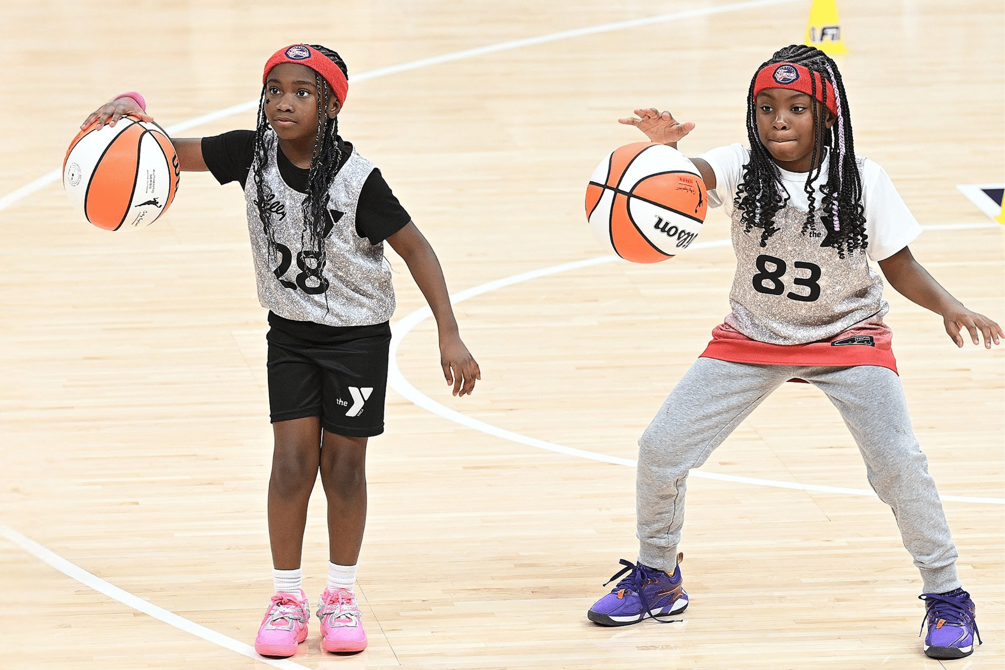 Two girls in YMCA basketball leagues practice dribbling.