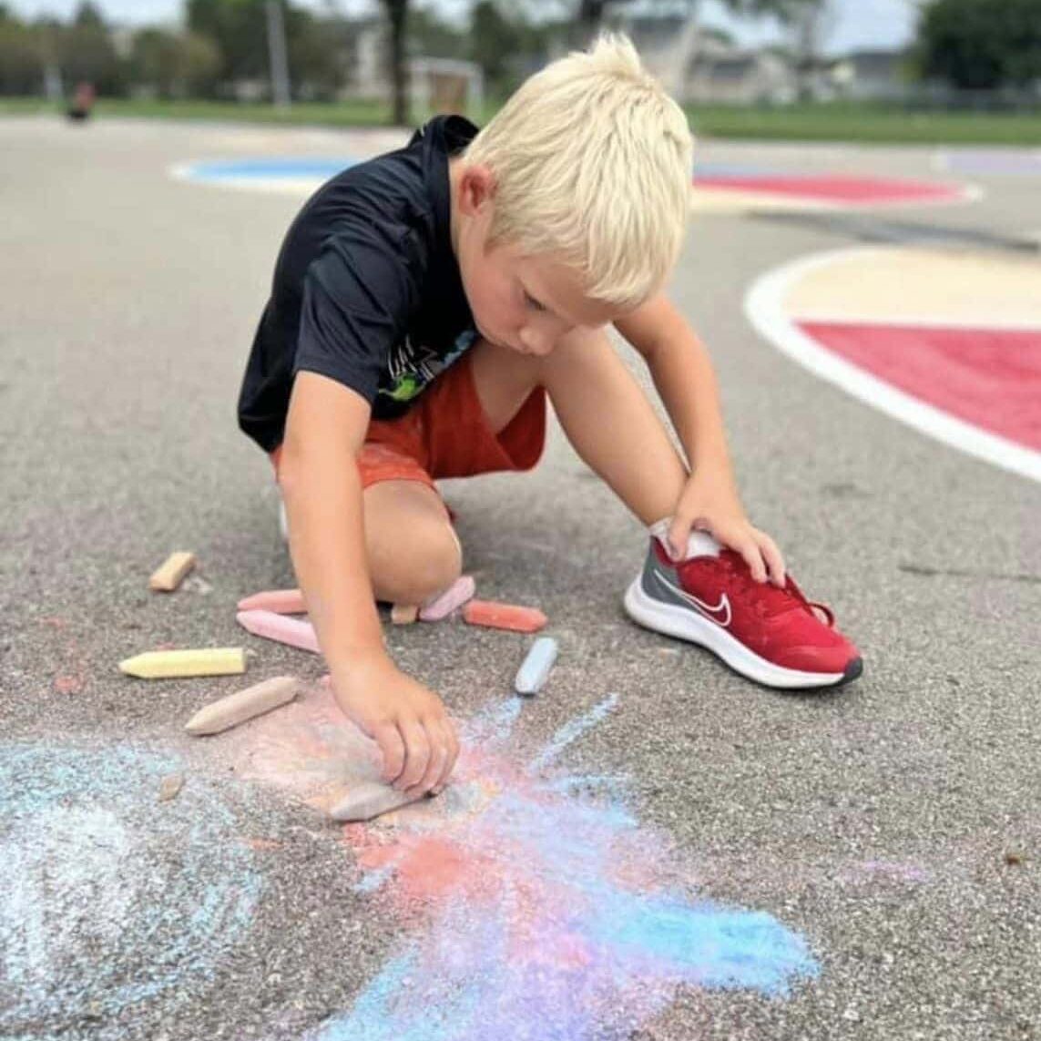 Child participating in school's out camp at the YMCA of Greater Indianapolis. Young boy is drawing with chalk.