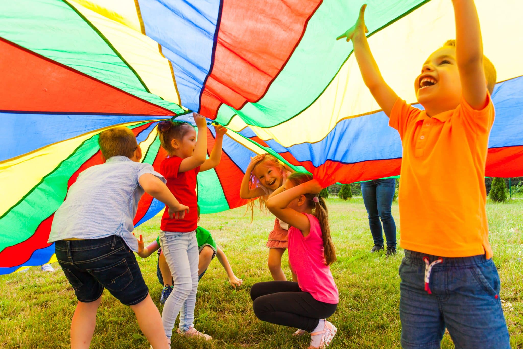 Children Participating in School's out Camp at their local YMCA. Children playing underneath a rainbow tent.